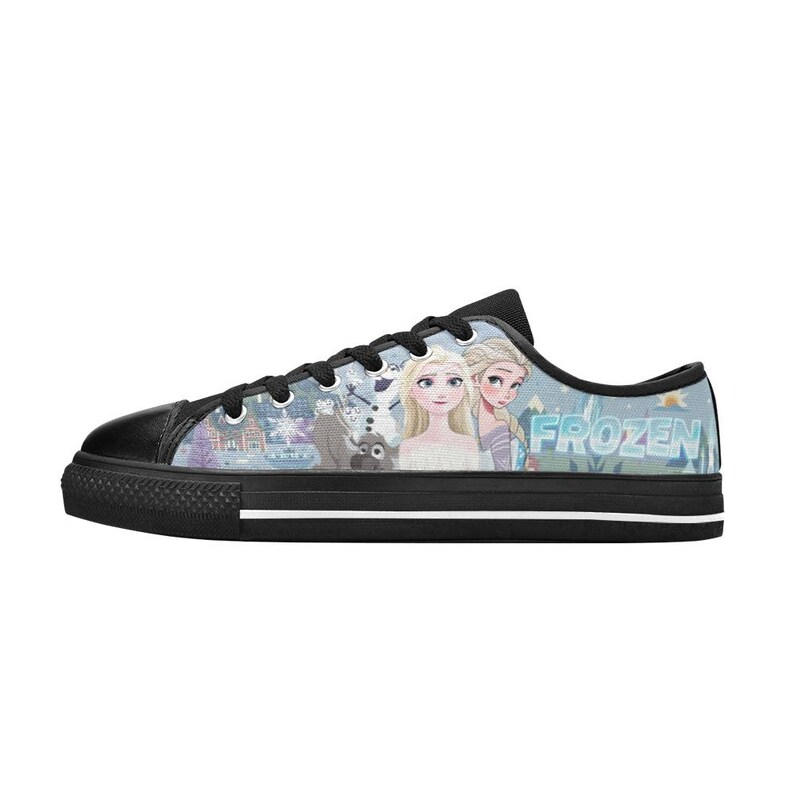May include: A low-top sneaker with a black rubber sole and toe cap, featuring a light blue patterned upper with illustrations of characters from Frozen, including Elsa and Anna, alongside the text Frozen in a stylized blue font on the side.