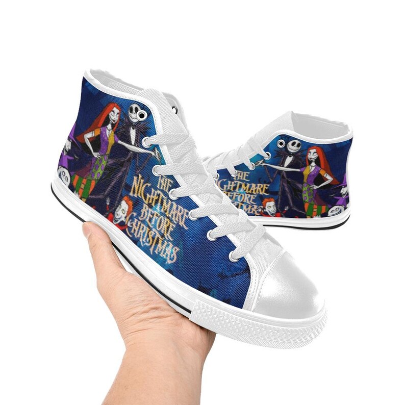 May include: High-top canvas sneakers featuring a blue background with characters from The Nightmare Before Christmas, including Jack Skellington and Sally. The shoes have white laces, white rubber toe caps, and the movie title printed in gold.