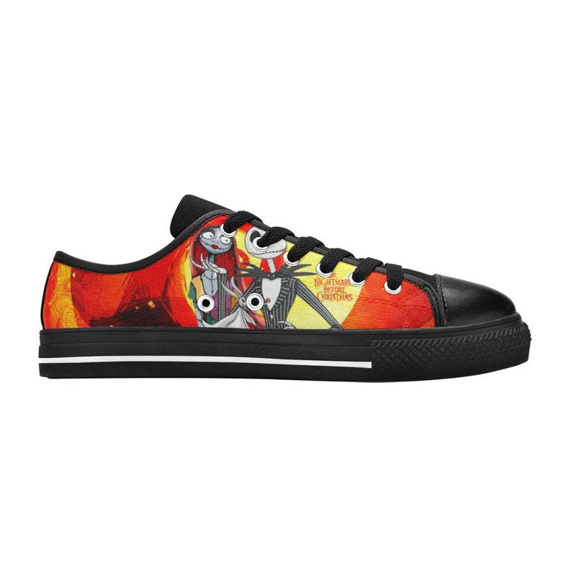 May include: A low-top trainer featuring a vibrant graphic print of Jack Skellington, Sally, and Zero from The Nightmare Before Christmas against a yellow and red background. The shoe has black laces, a black toe cap, and a black sole with white trim.