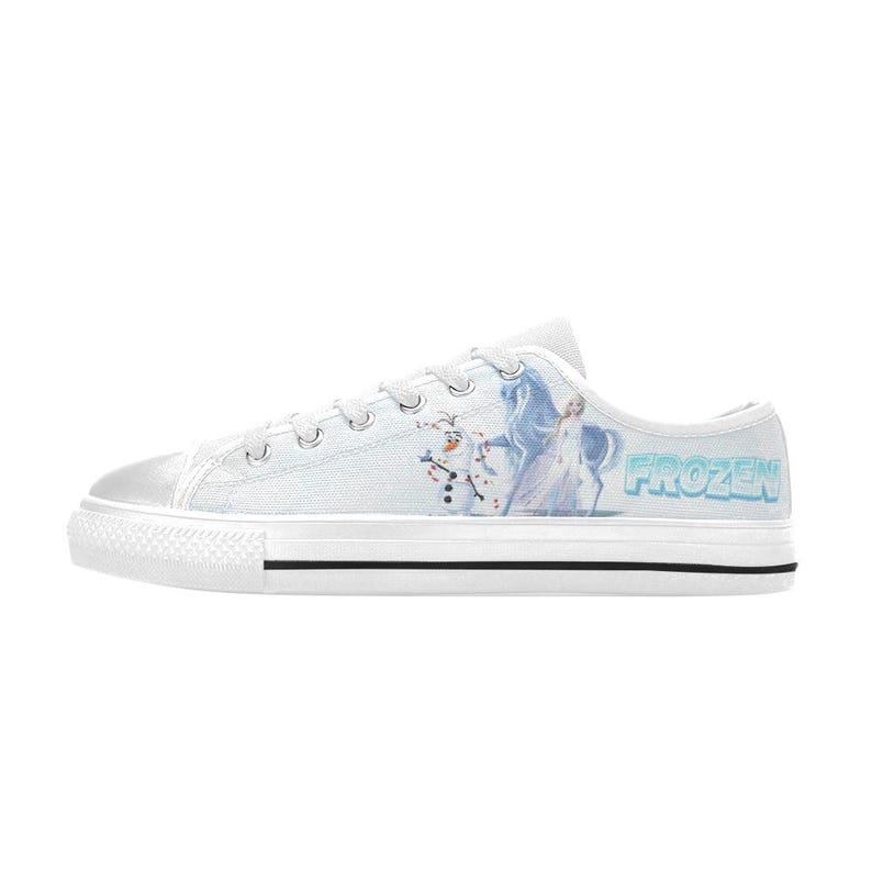 Peut inclure: Une basket basse en toile blanche orn&eacute;e d'un motif imprim&eacute; repr&eacute;sentant les personnages Olaf et Elsa de Frozen, ainsi que le logo bleu Frozen sur le c&ocirc;t&eacute;. La chaussure poss&egrave;de un bout en caoutchouc blanc, des lacets blancs et une semelle blanche.
