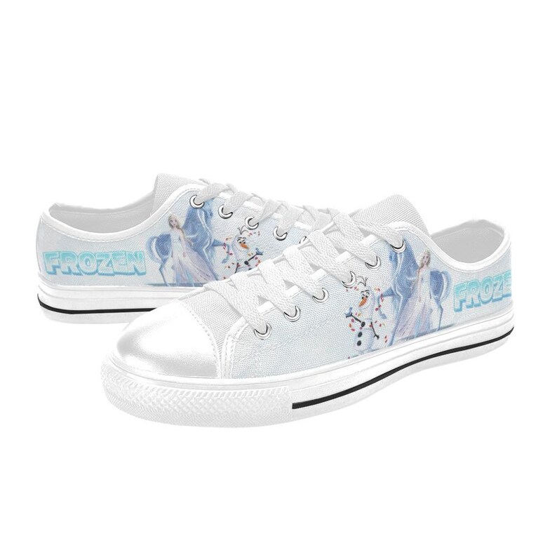 Peut inclure: Baskets basses en toile blanche avec un motif imprim&eacute; repr&eacute;sentant Elsa et Olaf de Frozen. Les chaussures ont des lacets blancs, un bout en caoutchouc blanc et une bande noire le long de la semelle. Le mot Frozen est imprim&eacute; en bleu sur le c&ocirc;t&eacute;.