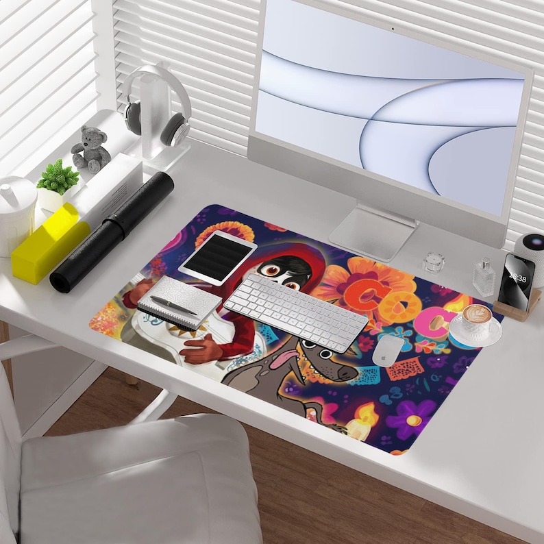 May include: A colorful desk mat featuring a vibrant design with cartoon characters, flowers, and the word "Coco". The mat includes a keyboard, mouse, tablet, and a cup of coffee, creating a lively workspace.