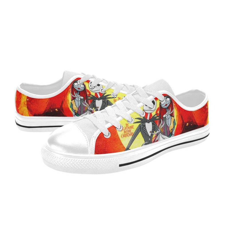 May include: Low-top canvas trainers featuring a vibrant graphic print of Jack Skellington and Sally from The Nightmare Before Christmas. The design includes a bright yellow and red background, white laces, white rubber toe caps, and white soles.