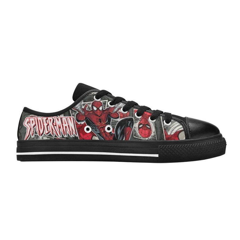 May include: A low-top sneaker featuring a black rubber sole with a white stripe and a black canvas upper printed with a comic book graphic of Spider-Man. The design includes the red and blue character in various poses and the text Spider-Man.