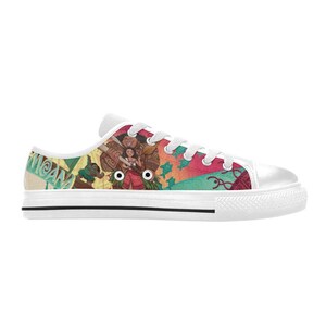 May include: White canvas low-top sneakers featuring a colorful design with characters and text from the animated movie "Moana". The design includes images of characters, and tropical elements. The sneakers have white laces and a white rubber sole.