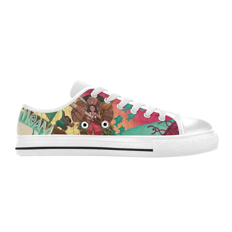 May include: White canvas low-top sneakers featuring a colorful design with characters and text from the animated movie "Moana". The design includes images of characters, and tropical elements. The sneakers have white laces and a white rubber sole.