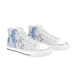 Pu&ograve; includere: Un paio di scarpe alte in tela bianca con una stampa grafica raffigurante un personaggio biondo in abito lungo, un cavallo blu e un pupazzo di neve. Le scarpe presentano lacci bianchi, punte in gomma bianca e una sottile striscia nera sulla suola.