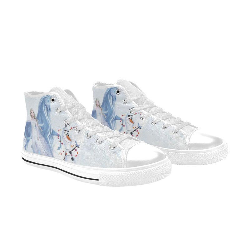 Pu&ograve; includere: Un paio di scarpe alte in tela bianca con una stampa grafica raffigurante un personaggio biondo in abito lungo, un cavallo blu e un pupazzo di neve. Le scarpe presentano lacci bianchi, punte in gomma bianca e una sottile striscia nera sulla suola.