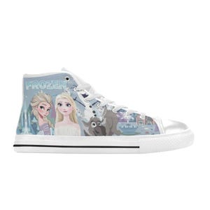 Pode incluir: Um t&ecirc;nis de cano alto com um esquema de cores azul claro e branco, apresentando uma estampa gr&aacute;fica dos personagens de Frozen, incluindo Elsa, Anna e Sven. O cal&ccedil;ado possui cadar&ccedil;os brancos, biqueira de borracha branca e sola branca com listra.