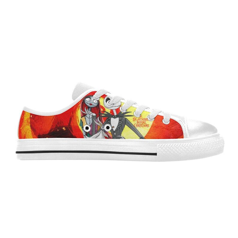 May include: A low-top canvas trainer featuring a vibrant graphic print of Jack Skellington, Sally, and Zero from The Nightmare Before Christmas. The shoe has white laces, a white rubber toe cap, and a white sole with a thin black stripe detail.