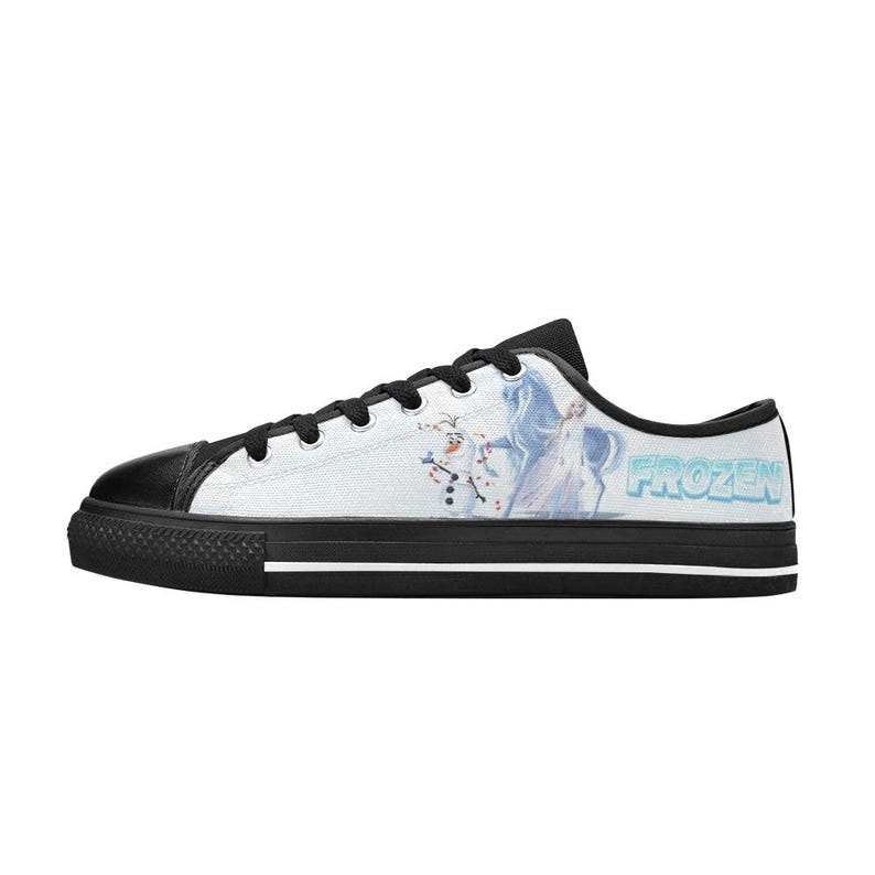 Peut inclure: Une basket basse en toile avec un bout en caoutchouc noir, des lacets noirs et une semelle noire avec une rayure blanche. Le panneau lat&eacute;ral pr&eacute;sente un graphique d'Olaf et Elsa de Frozen, avec le mot FROZEN imprim&eacute; en lettres bleu clair.