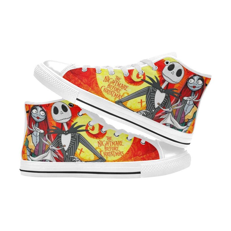 May include: High-top canvas sneakers featuring a vibrant yellow, orange, and red graphic print of Jack Skellington, Sally, and Zero from The Nightmare Before Christmas. The shoes have white laces, white rubber toe caps, and white soles with black trim.