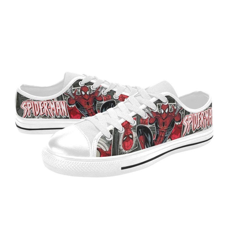 May include: A pair of low-top canvas sneakers featuring a red and black comic book print of Spider-Man. The shoes have white laces, white rubber toe caps, and white soles. The text SPIDER-MAN is printed in a bold, stylized red font on the sides.