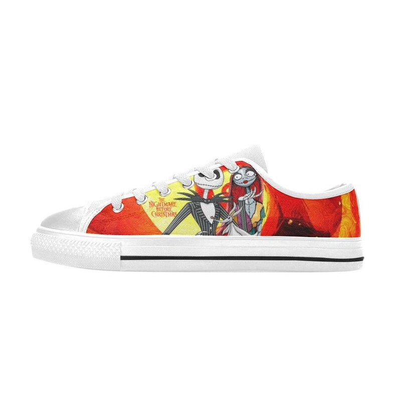 May include: A low-top canvas trainer featuring a vibrant red and yellow graphic print of Jack Skellington, Sally, and Zero from The Nightmare Before Christmas. The shoe has white laces, a white rubber toe cap, and a white sole with a black stripe.