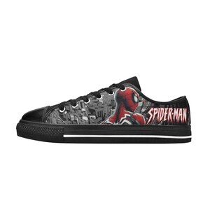 May include: Black canvas low-top sneakers featuring a Spiderman graphic. The design includes a cityscape background and the word "SPIDER-MAN" in red. The sneakers have black soles and laces.