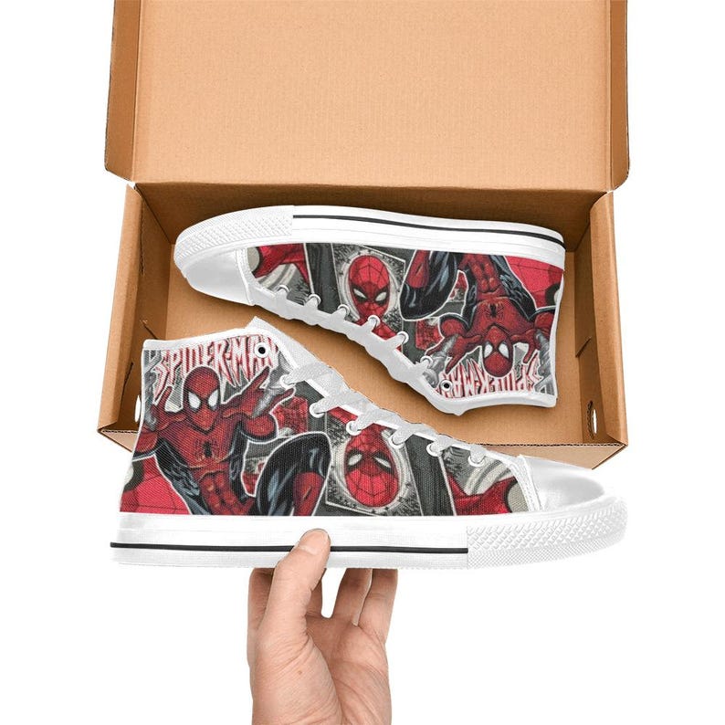 May include: A pair of high-top canvas sneakers featuring a red and black comic book print of Spider-Man. The shoes have white laces, white rubber toe caps, and white soles. The word Spider-Man is printed in red on the side of the canvas fabric.