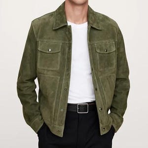 Puede incluir: Chaqueta de ante verde oliva con dos bolsillos en el pecho y cierre de botones. La chaqueta tiene un cuello cl&aacute;sico y se combina con una camiseta blanca, pantalones negros y un cintur&oacute;n negro.