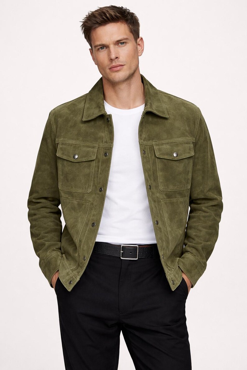 Puede incluir: Chaqueta de ante verde oliva con dos bolsillos en el pecho y dos bolsillos inferiores. La chaqueta est&aacute; abotonada y se lleva sobre una camiseta blanca y pantalones negros. Se ve un cintur&oacute;n negro con hebilla plateada.
