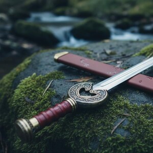 May include: A decorative sword with a silver blade and a detailed brass hilt featuring a heart-shaped design. The handle is wrapped in red leather. The sword rests on a moss-covered rock, with a red sheath nearby.