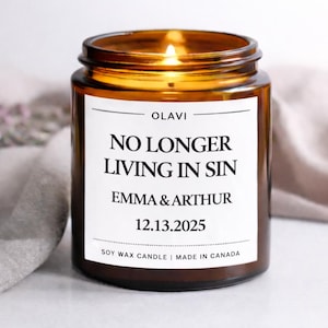 Könnte beinhalten: Eine brennende Sojawachskerze in einem braunen Glas. Die Kerze hat ein weißes Etikett mit dem Text "NO LONGER LIVING IN SIN" und den Namen "EMMA & ARTHUR" mit dem Datum "12.13.2025". Hergestellt in Kanada.