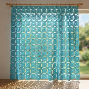 Könnte beinhalten: Ein türkisfarbener Häkelvorhang mit einem sich wiederholenden kreisförmigen Motivmuster. Der Vorhang hängt an einer Holzstange mit Ringen und zeigt ein komplexes durchbrochenes Design, das Licht durch die Garnstruktur lässt.