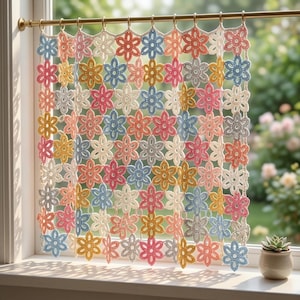 May include: A crochet curtain with a floral design hangs in a window. The curtain is made up of a grid of flowers in pastel shades of pink, blue, yellow, and cream. It is suspended from a gold-coloured rod, creating a decorative window treatment.