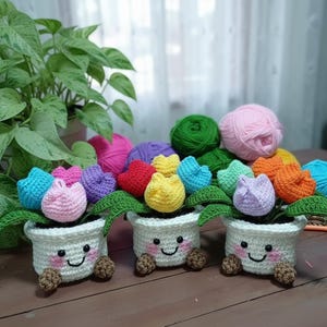 May include: A set of three ceramic mugs with a speckled, cream-colored glaze. Each mug features a different hand-painted floral design in shades of blue, green, and yellow. The mugs have a simple, rounded shape.