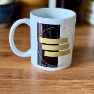 May include: A trio of ceramic mugs with a speckled, matte finish in light blue, cream, and grey. The mugs have a simple, modern design with a rounded shape and a comfortable handle.