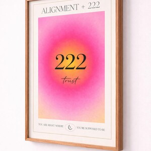 May include: Framed art print with a gradient background of pink, yellow, and orange. The print features the text "ALIGNMENT + 222" at the top, with "222" and "trust" in the center. The bottom reads "YOU ARE RIGHT WHERE" and "YOU'RE SUPPOSED TO BE".