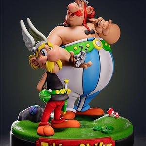 Op de afbeelding: Gedetailleerd beeldje van Asterix en Obelix, twee stripfiguren, staand op een groene basis. Asterix draagt een gevleugelde helm, een zwarte top, een rode broek en oranje schoenen. Obelix heeft een rode snor, een blauw-wit gestreepte broek en houdt een kleine hond vast. De basis heeft de tekst "Asterix & Obelix".