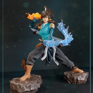 May include: A detailed figurine of a female character in a dynamic pose, wielding fire and water elements. She wears a teal top, gray pants, and brown boots. The figure stands on two rocky platforms, with flames in one hand and a water effect in the other.