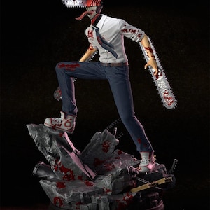 Puede incluir: Figura detallada de un personaje de la serie de anime Chainsaw Man. La figura está posada dinámicamente, con una cabeza y un brazo de motosierra, vistiendo una camisa blanca, vaqueros azules y zapatillas. La base es un terreno rocoso con salpicaduras de sangre.