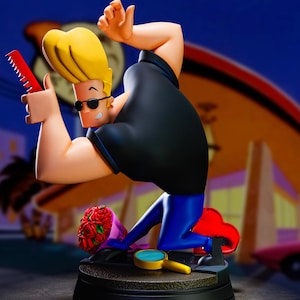May include: A figurine of Johnny Bravo in a black shirt and blue pants, holding a red comb. He kneels near a bouquet of red roses and a magnifying glass. The figure has yellow hair and sunglasses.
