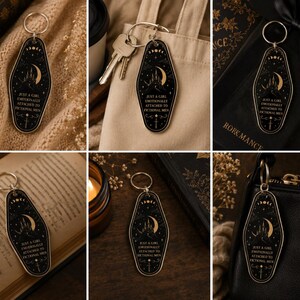 May include: Black keychain with a gold-colored moon and castle design. The text on the keychain reads "JUST A GIRL EMOTIONALLY ATTACHED TO FICTIONAL MEN". The keychain has a silver-colored ring.