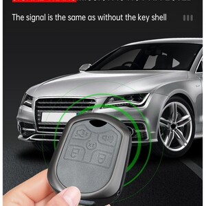 May include: A black car key fob made of zinc alloy is held in front of a silver car. The key fob has buttons for locking and unlocking the car. Text on the image reads "ZINC ALLOY MATERIAL SIGNAL TRANSMISSION IS NOT AFFECTED".