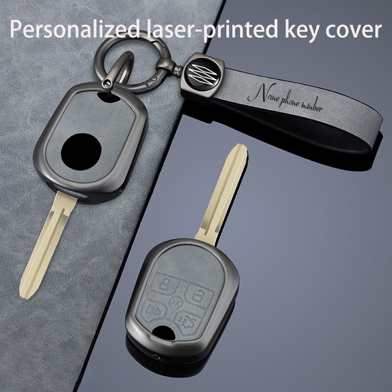May include: A set of personalized laser-printed key covers. The keys are gray with a silver key ring and a gray leather strap. The strap has the text "Name phone number" printed on it. The key covers have a black circle and the key has a silver blade.