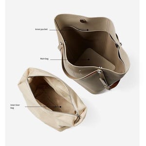 May include: A taupe tote bag with an open top, revealing an inner pocket and main bag compartment. A separate beige inner liner bag with a zip is also shown. The bag is made of a soft material.