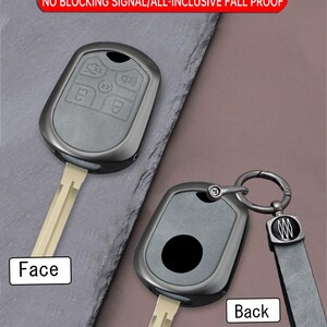 May include: Two car key shells made of zinc alloy. The face of the key shell has buttons, while the back has a circular design. The key shells are dark gray and have a key ring and a black leather strap. The text on the image says "METAL KEY CASE".