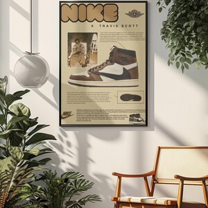 May include: A framed poster featuring a Nike X Travis Scott sneaker design. The poster has a beige background with the Nike logo in a brown, blocky font. The sneaker is brown, white, and black. The poster includes a photo of Travis Scott and text.