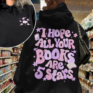 May include: Black hoodie with the text "I Hope All Your Books Are 5 Stars" in pink and purple. The hoodie also features a small design of stars and a book on the front.