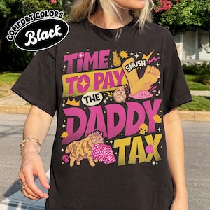 Puede incluir: Una camiseta negra con un estampado gráfico que incluye el texto "TIME TO PAY THE DADDY TAX". El diseño muestra una piña, un pie con la etiqueta "SMUSH", un hámster, un gato con corona y gafas sosteniendo unos pantalones cortos estampados, calaveras y una bomba.