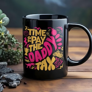 以下が含まれることがあります： 黒いセラミック製のマグカップで、黄色とピンクの文字で「TIME TO PAY THE DADDY TAX」と書かれたグラフィックデザインが施されています。イラストには、猫、爆弾、トロフィー、オートバイ、恐竜、稲妻の小さなアイコンが黄色とピンクで描かれています。