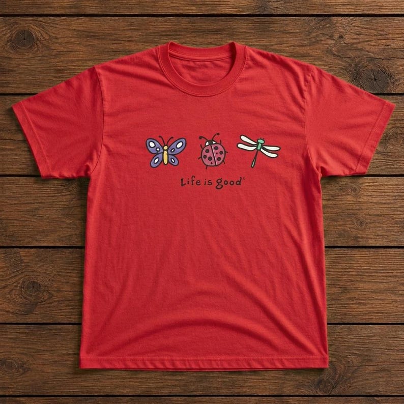 May include: A red t-shirt featuring a butterfly, ladybug, and dragonfly graphic. The phrase "Life is good" is printed below the illustrations. The shirt is made of a soft material and has a crew neck.