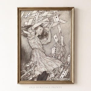 Op de afbeelding: Een ingelijste zwart-witillustratie van een persoon in een jurk, omringd door een werveling van vliegende speelkaarten. Het kunstwerk bevat gedetailleerd lijnwerk en schaduw, en toont een dynamische scène met een kleine hagedis onderaan.
