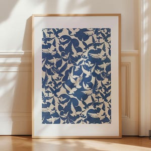 May include: A rectangular wall art print in a light wood frame featuring a repeating pattern of dark blue birds in flight against a cream-colored background. The artwork is displayed vertically, showcasing a dense arrangement of avian silhouettes.