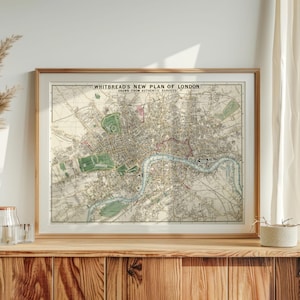 Op de afbeelding: Een ingelijste vintage kaart getiteld Whitbread's New Plan of London, Drawn from Authentic Surveys. De kaart toont een gedetailleerd stratenplan, de rivier de Theems in blauw en groene parkgebieden, geplaatst in een licht houten lijst.
