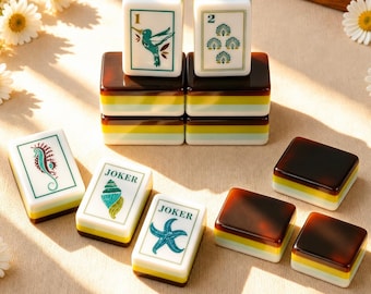 May include: A set of rectangular mahjong tiles featuring white faces with green and brown illustrations of a hummingbird, a seahorse, a starfish, and a seashell, alongside tiles labeled with the number 1, 2, or the word JOKER, all with dark brown backs.