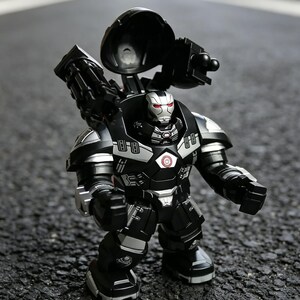Puede incluir: Una figura de acci&oacute;n negra y plateada de un personaje con forma de robot con un arma grande en la espalda. La figura tiene ojos rojos y un emblema circular en el pecho. La figura est&aacute; sobre una superficie gris oscura.