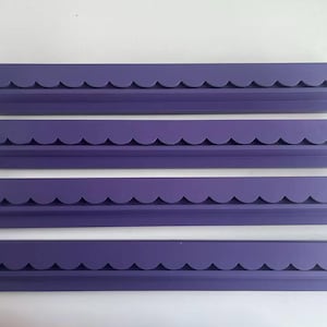May include: Four identical purple wall shelves arranged in a vertical stack. Each shelf features a long, rectangular base with a distinct scalloped edge design along the front, providing a consistent look across all four individual units.