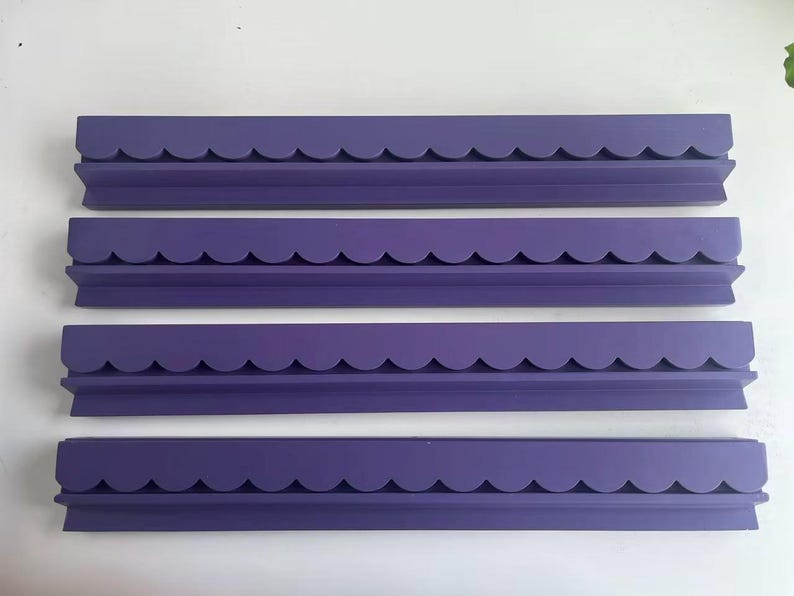 May include: Four identical purple wall shelves arranged in a vertical stack. Each shelf features a long, rectangular base with a distinct scalloped edge design along the front, providing a consistent look across all four individual units.